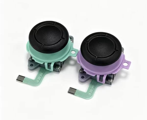 Two small electronic components with black circular tops, mint green plastic bases, and purple plastic side tabs, shown on a clean white background.