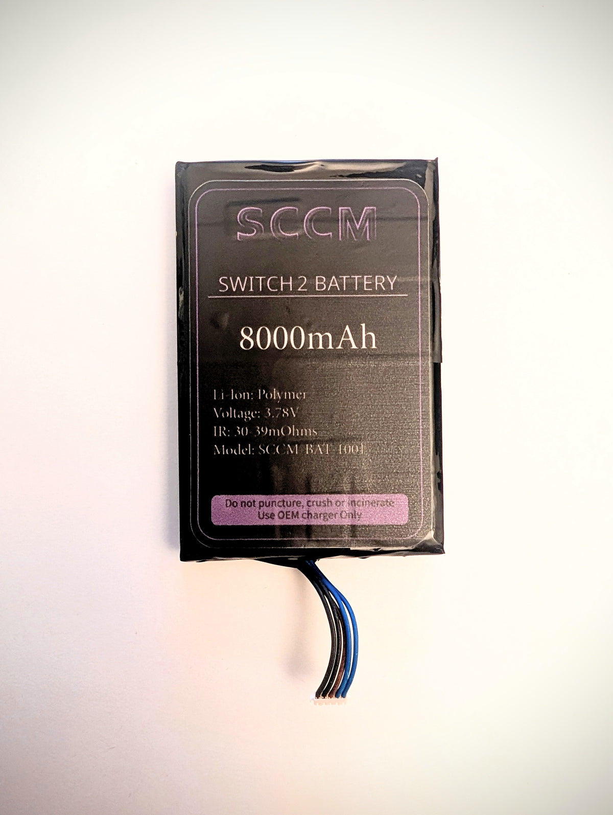 A black SCCM Switch2 Battery 8000mAh, model SCCM BAT 1001, shown in its plastic packaging with three wire leads extending from the bottom, set against a plain white background.